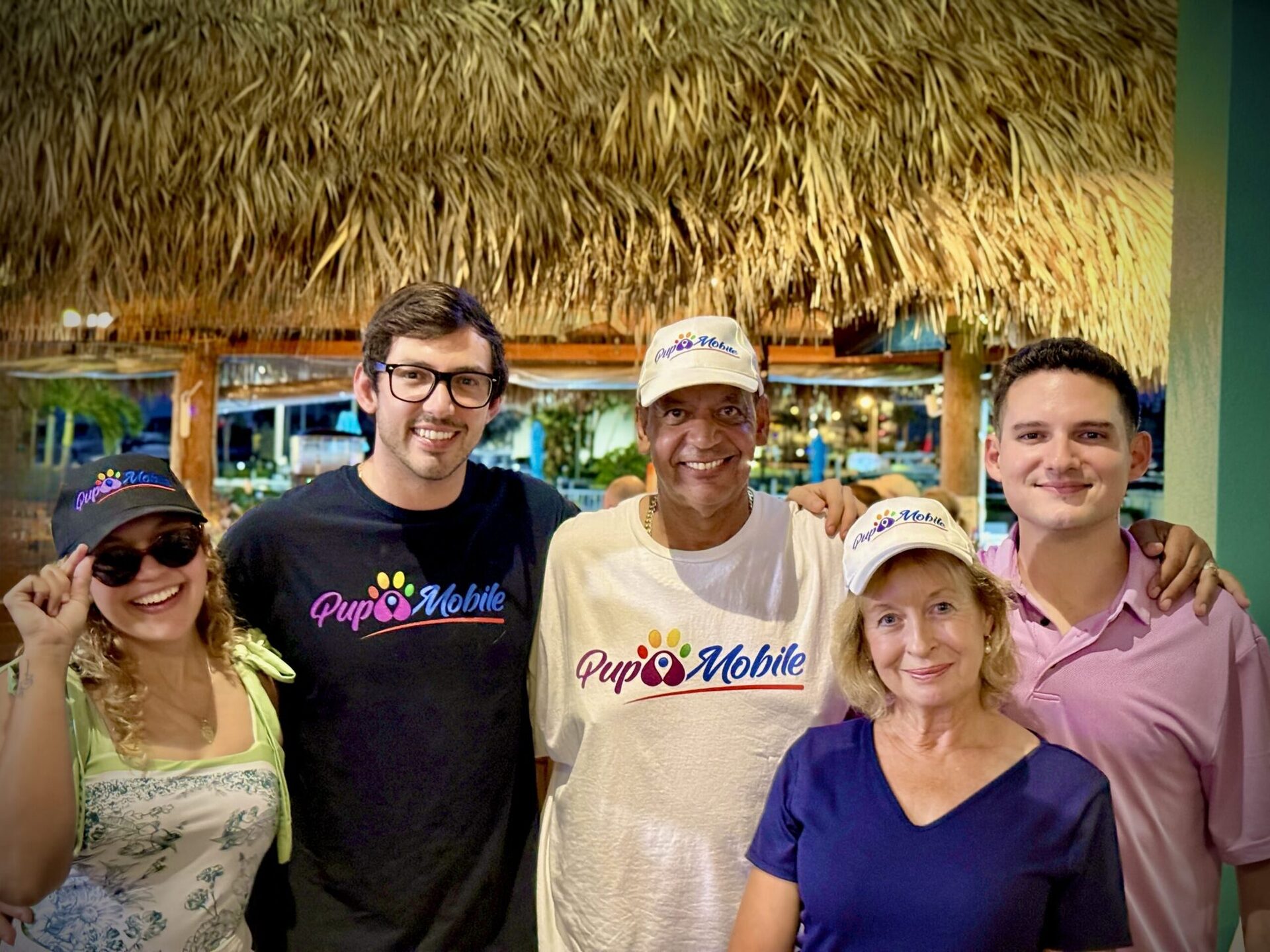 The Pup Mobile crew in branded shirts and hats at a tiki bar