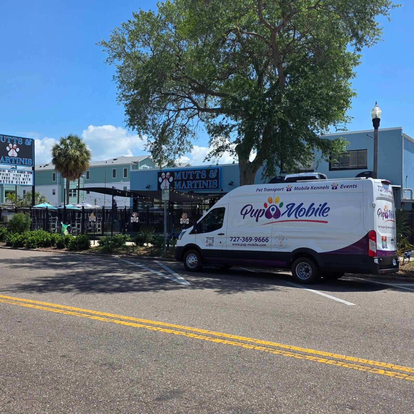 The Pup Mobile van on a Gulfport street under live oaks